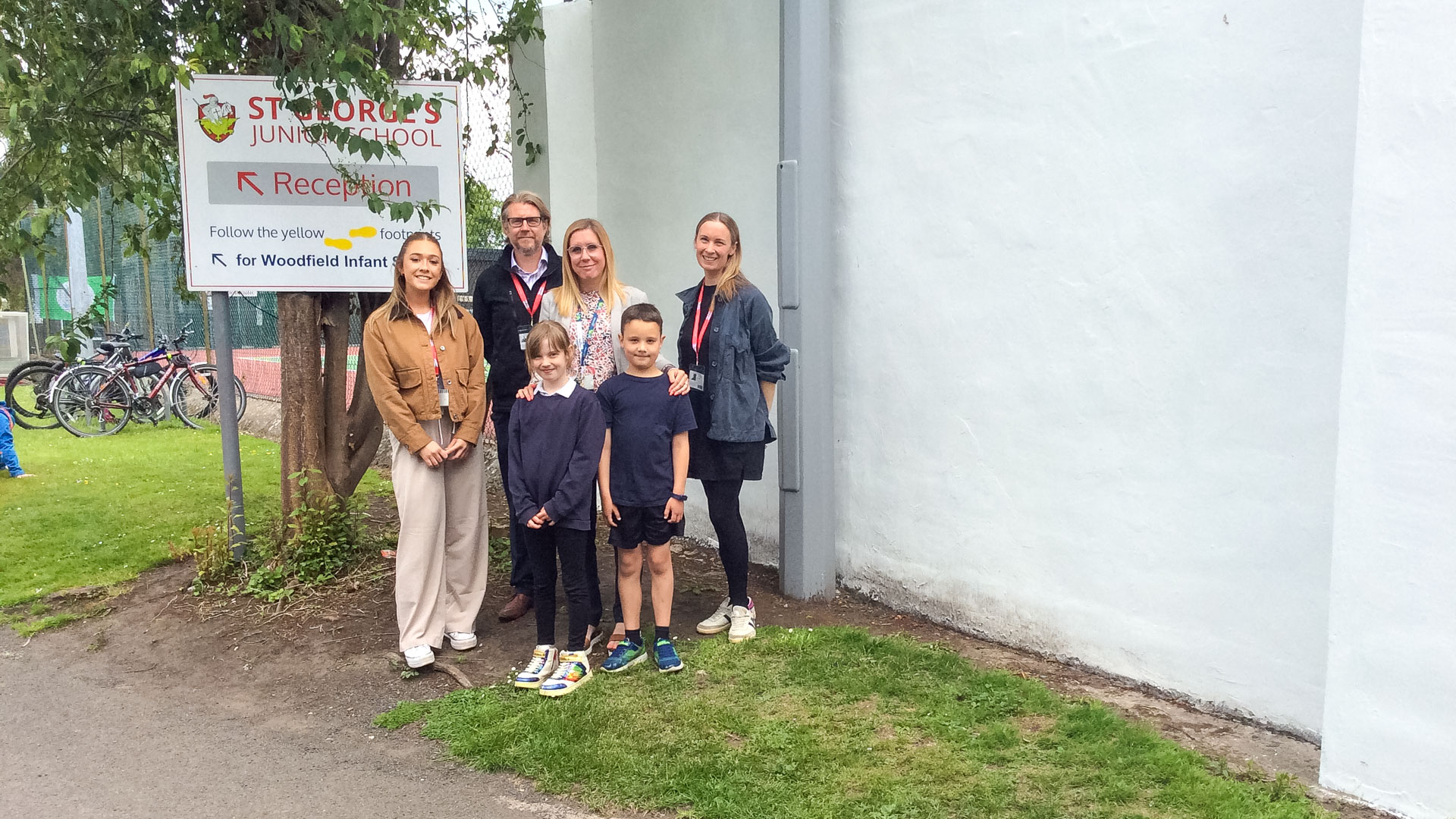 Several individuals of varying ages and backgrounds pose in front of a new painted wall, showcasing a sense of community.